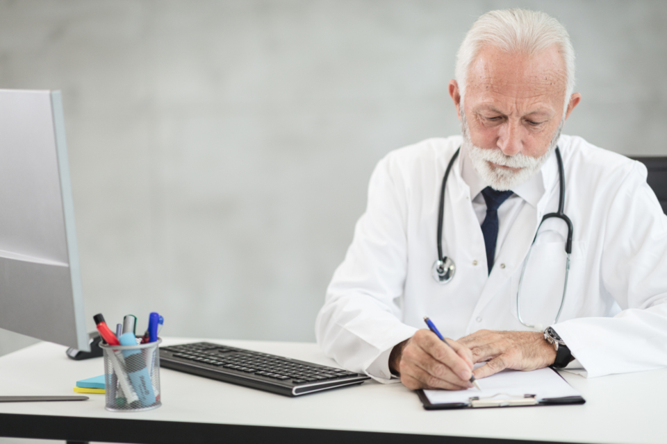 A doctor filling in a visit form at their desk